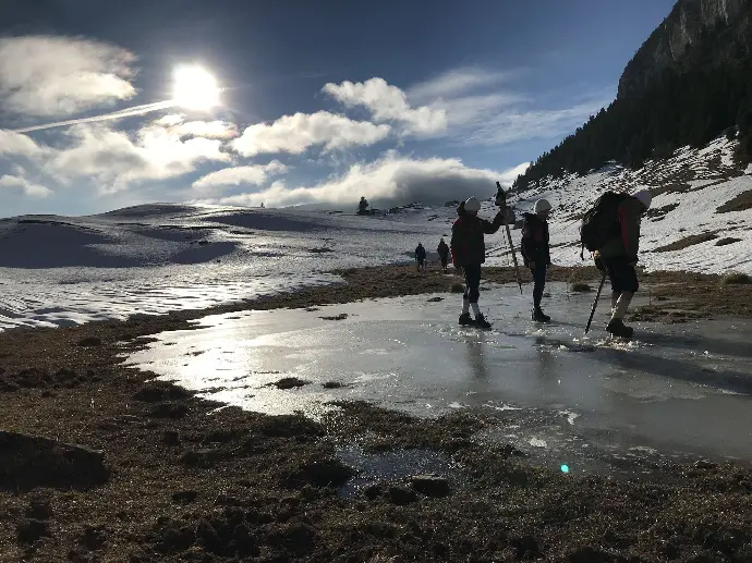 Un étang en montagne traversé par des scouts à pied